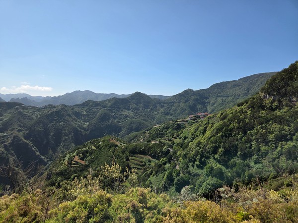 Vistas del macizo de Anaga con laderas verdes, barrancos profundos y caseríos dispersos bajo cielo azul.