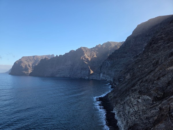Imponentes acantilados basálticos de Los Gigantes cayendo al Atlántico, con el mar en calma y cielo despejado.